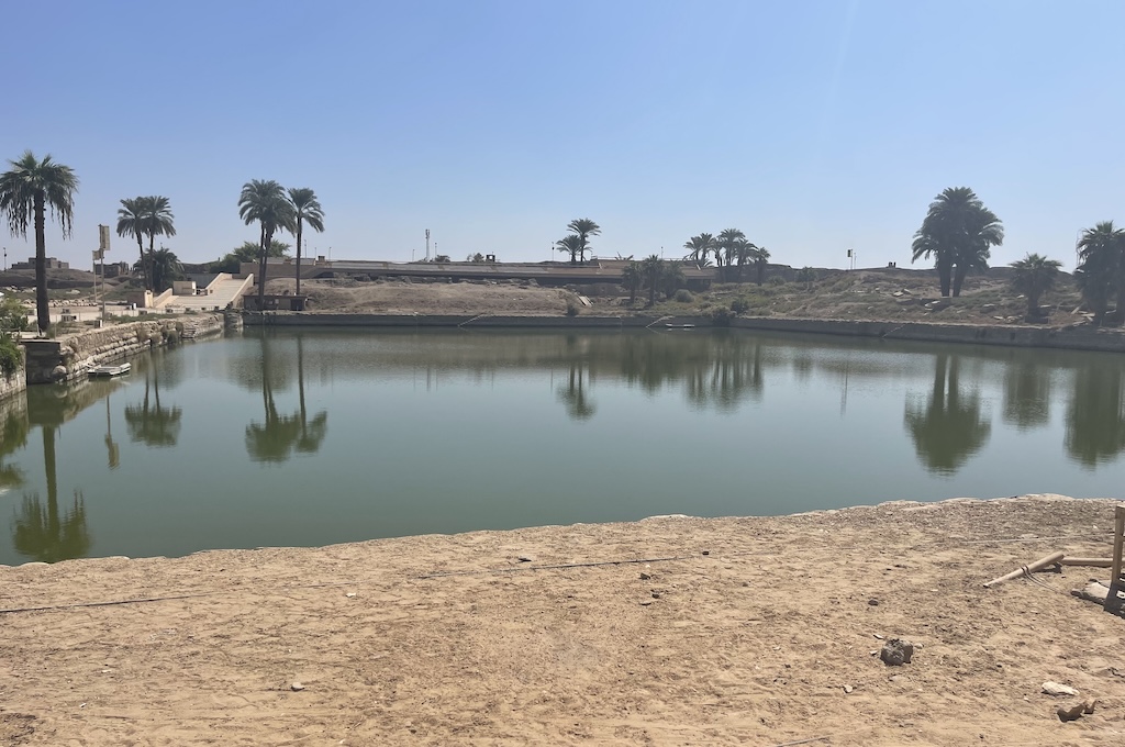 Der Heilige See im Karnak-Tempel von Luxor, umgeben von Palmen